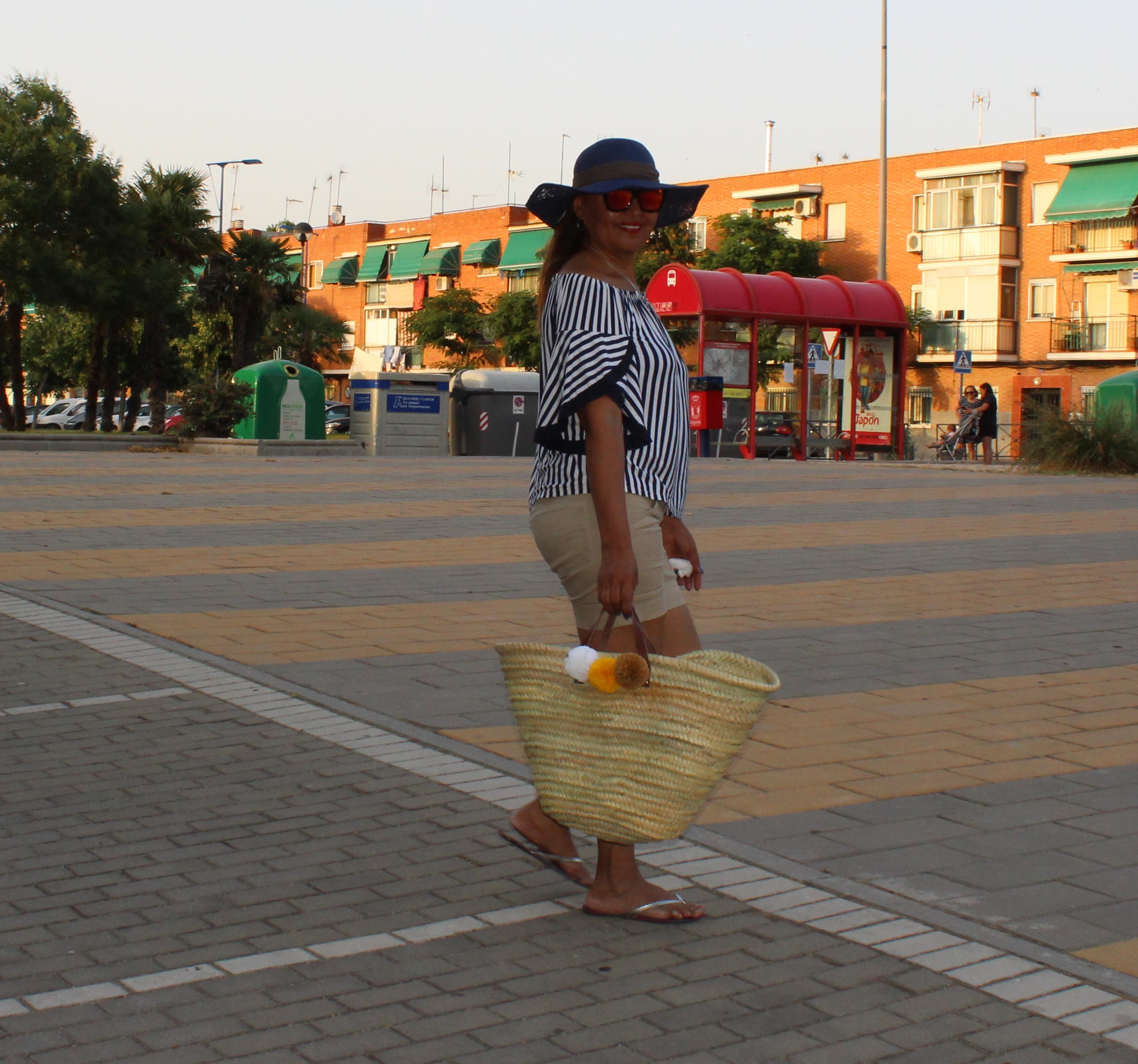 Look de verano compuesto Por:
Pamela azul, gafas espejo rojo, cesta de rafia con pompones, blusa escote de barco y pantalon corto.